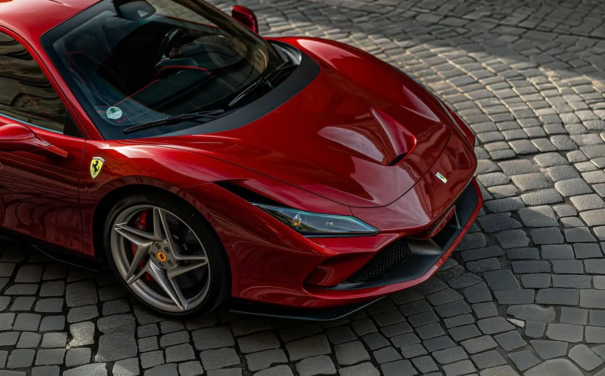 Red Ferrari with window tinting parked on a cobblestone street