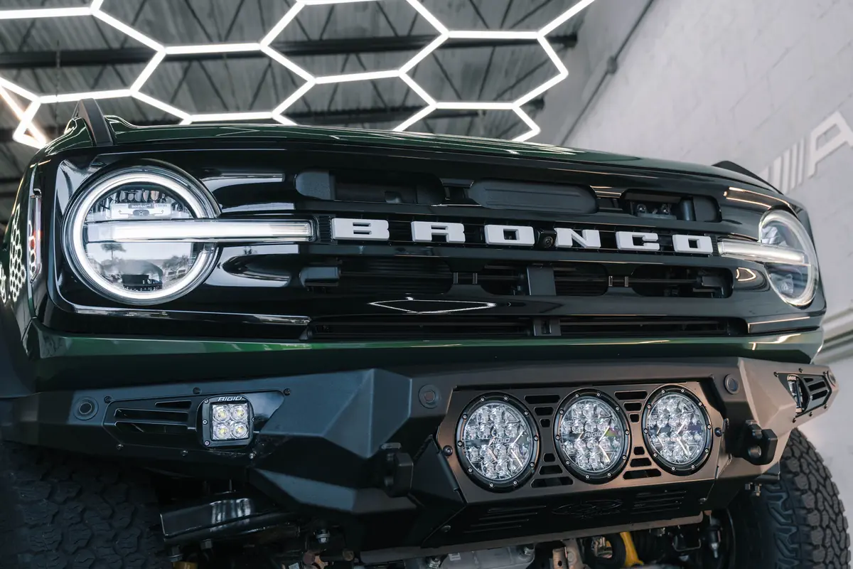 Green Ford Bronco with an aftermarket bumper and LED light pods, accessories installed at Ecophant Auto in Boca Raton