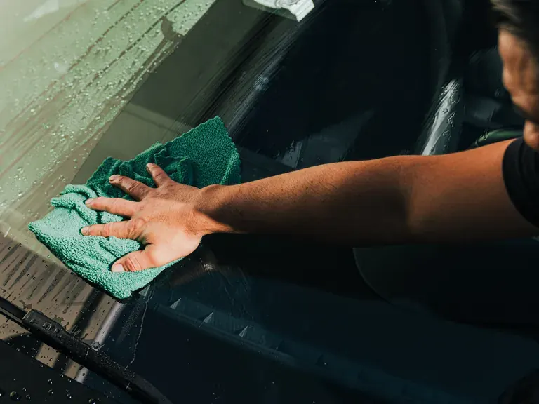 Ecophant Auto technician hand-drying a windshield during auto detailing